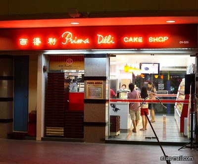 PrimaDéli cake shop front with customers inside and a bright neon sign.