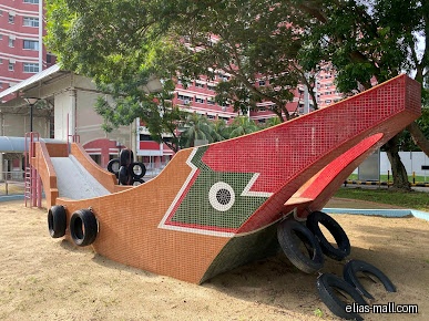 The image shows a boat-shaped playground structure with a slide and tires.