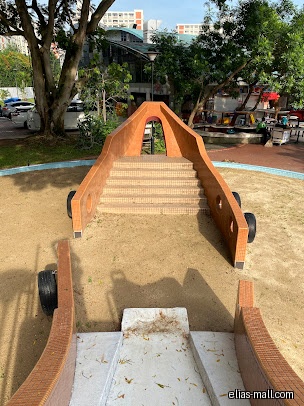 A playground with a boat-shaped structure and a slide in a sandy area.