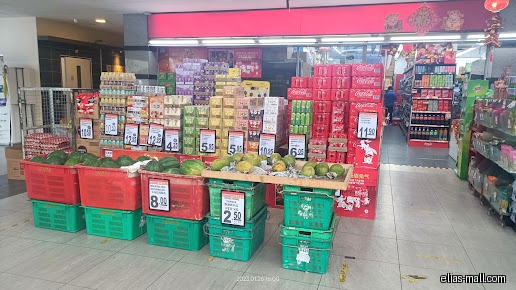 Sheng Siong Supermarket display of watermelons, drinks, and other products with price tags.
