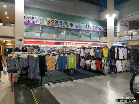 Clothing racks are displayed in front of a U Stars Supermarket in a mall.