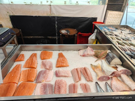 A display of fresh fish fillets and whole fish on ice at a market.