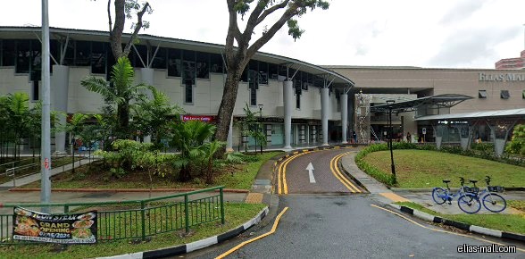 Exterior view of Elias Mall with shops and a road leading to it.