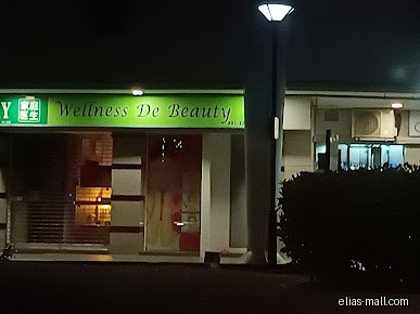 The shop front of Wellness De Beauty is visible at night.