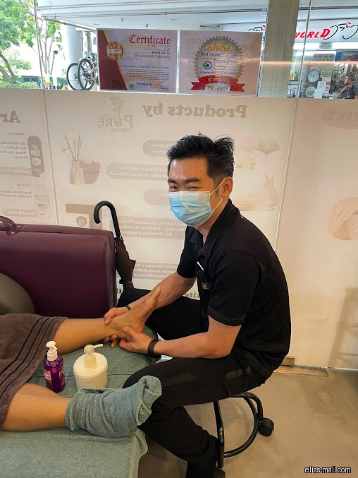 A massage therapist wearing a mask massages a client's foot.