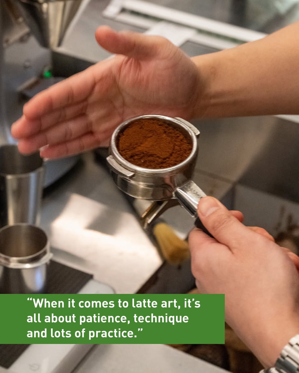 Intricate latte art pattern, possibly a rosetta, in a coffee cup