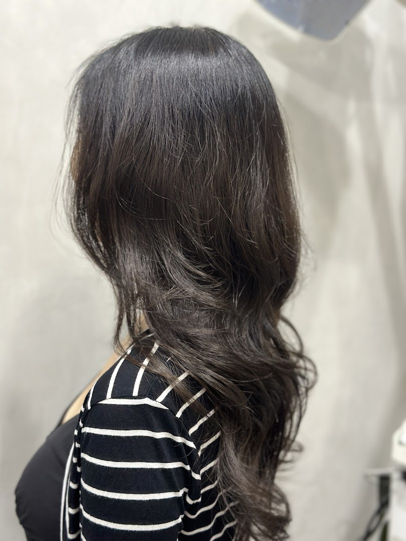 A person showcasing healthy, dark hair with soft waves, likely after a salon treatment.