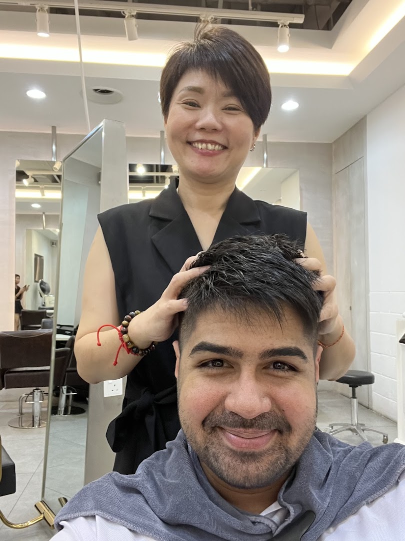 A smiling stylist gives a head massage to a happy male client in a modern salon setting.