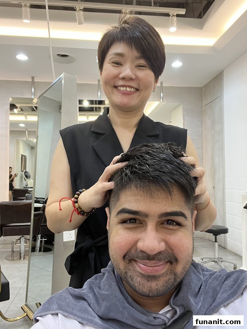 A smiling stylist gives a head massage to a happy male client in a modern salon setting.