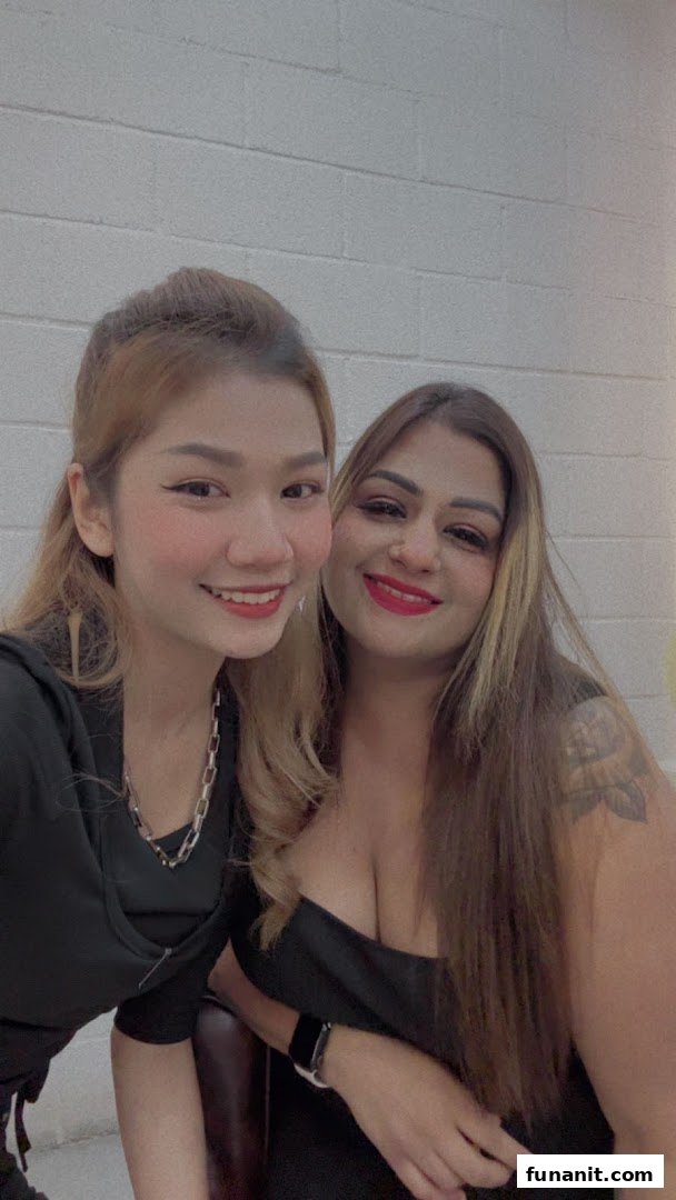 Two smiling women, possibly staff or customers, pose for a photo against a white brick wall.