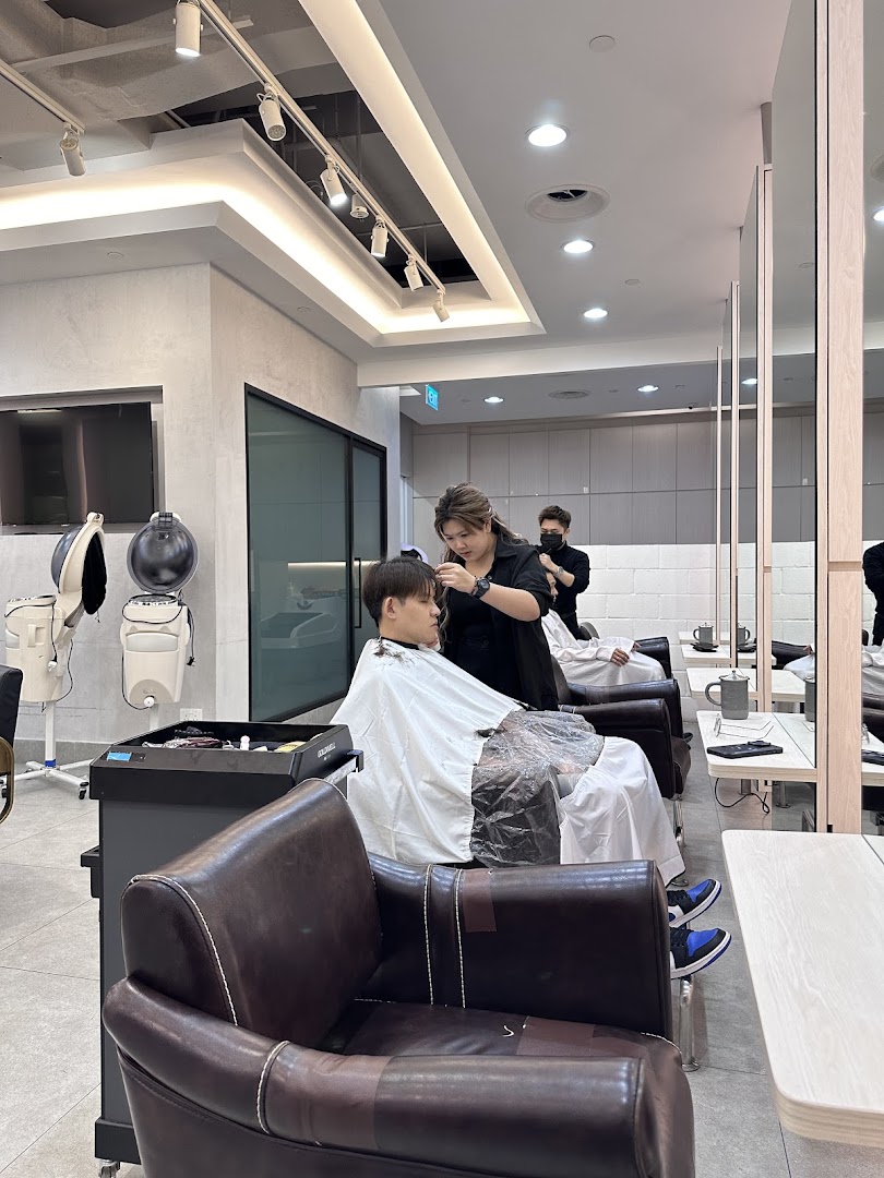 A customer receives a haircut from a stylist in a modern, well-lit hair salon.