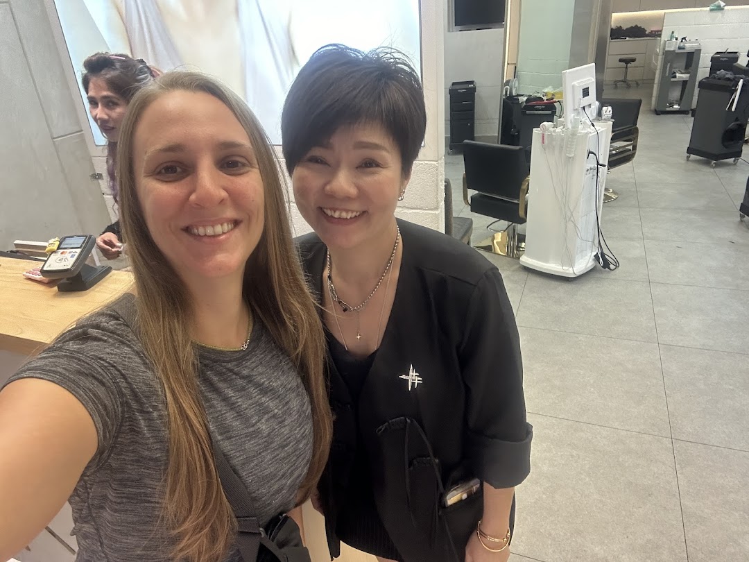 Two smiling women, a customer and a staff member, inside a modern beauty salon.