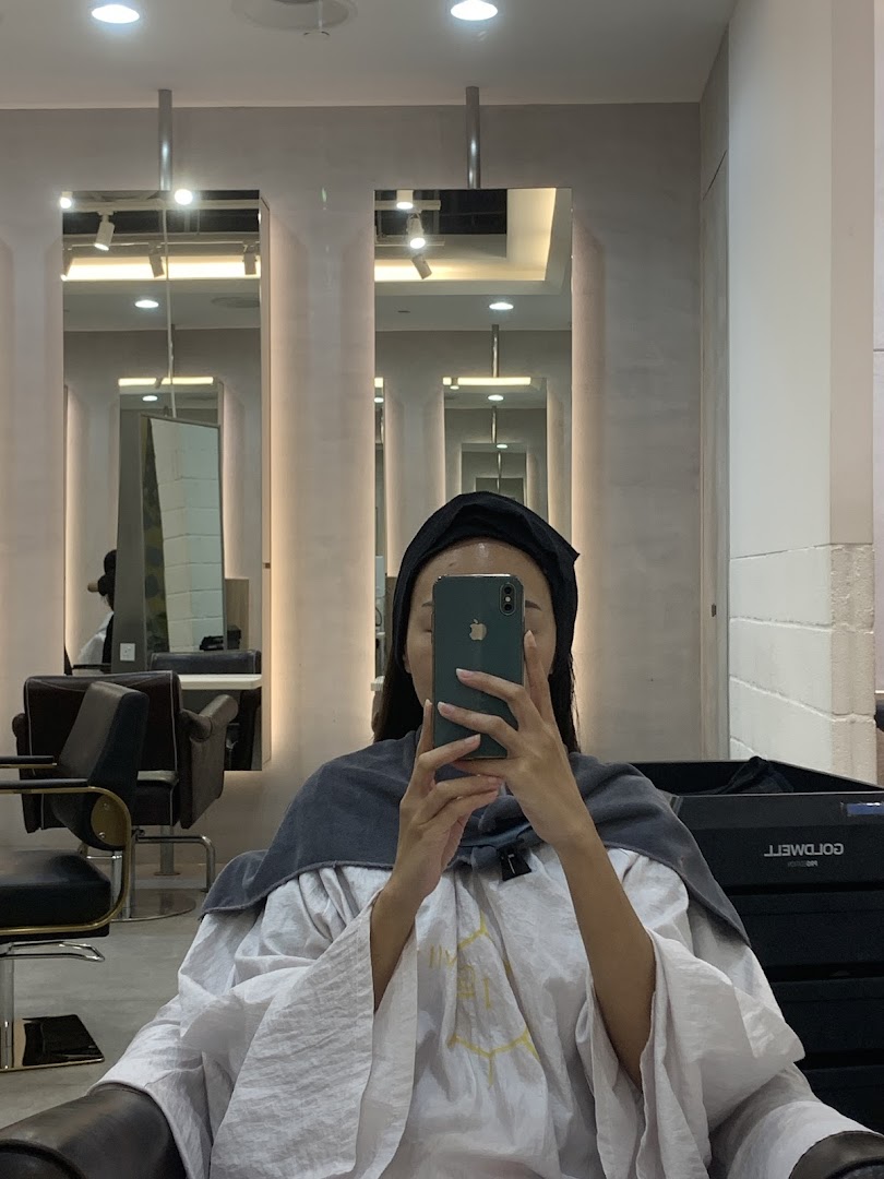 A customer takes a mirror selfie inside a modern hair salon, showcasing the stylish interior.