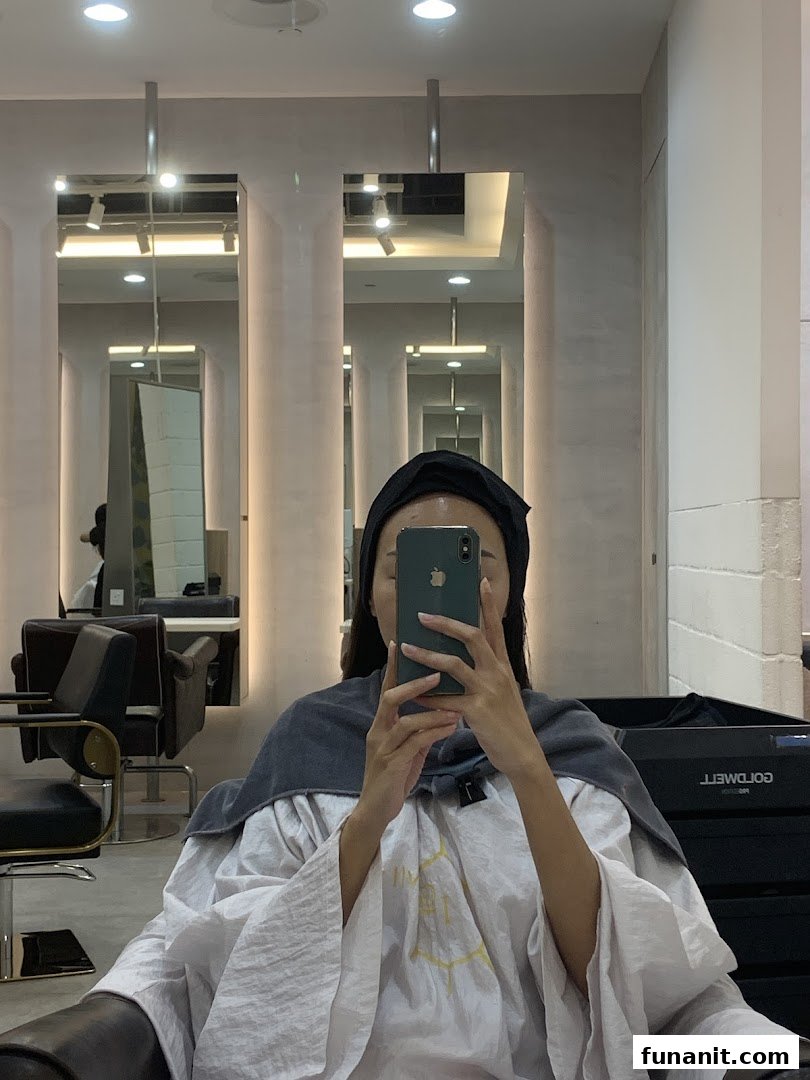 A customer takes a mirror selfie inside a modern hair salon, showcasing the stylish interior.
