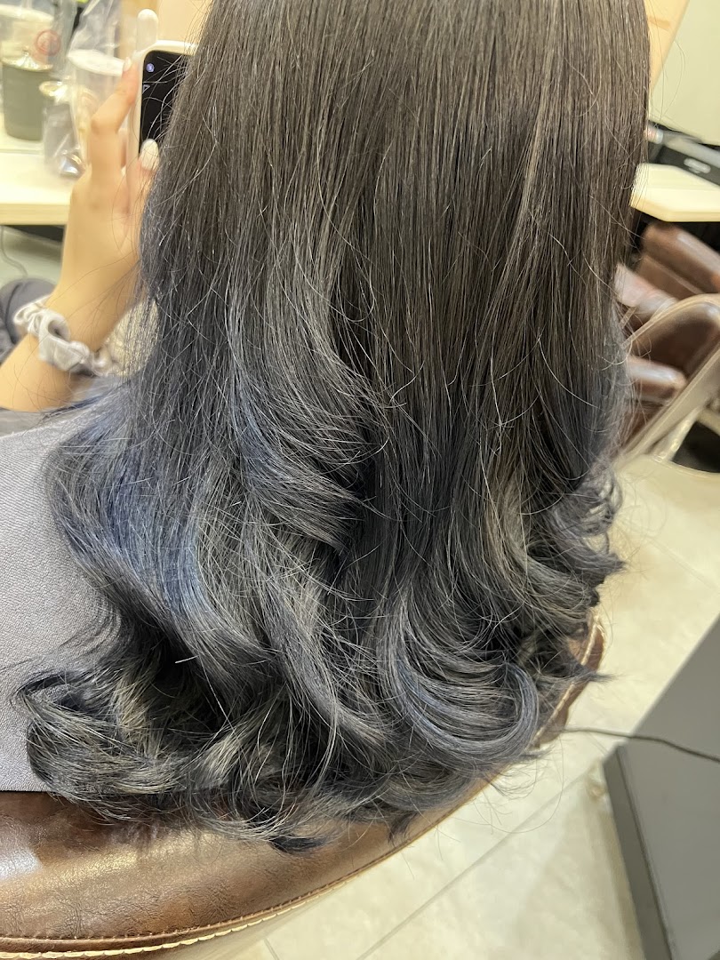 Close-up of a person's styled hair with subtle blue highlights, showcasing hair treatment results.