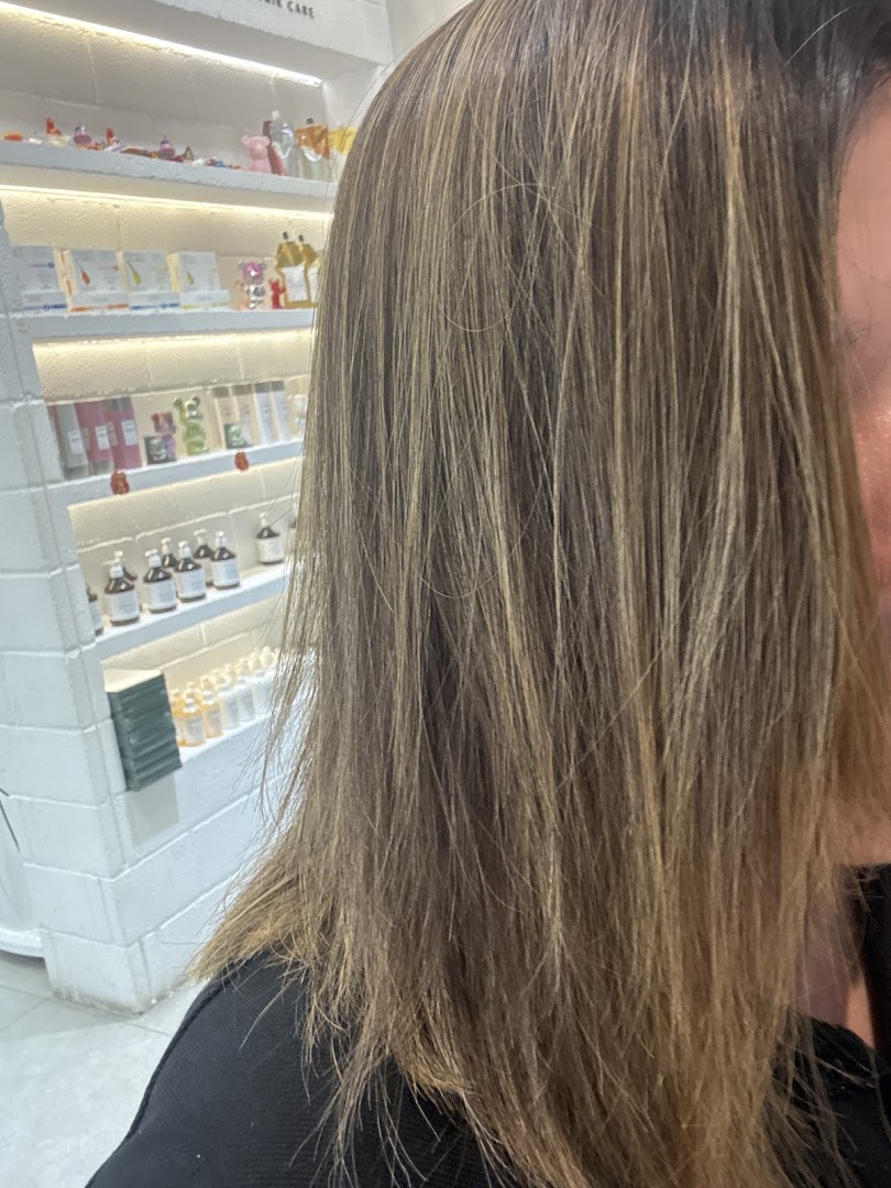 Close-up of a customer's hair, showcasing hair care products displayed on shelves in the background.