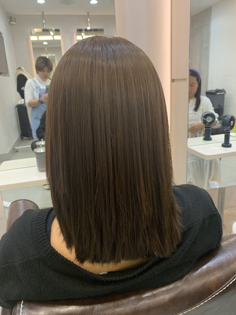A customer's freshly styled, straight brown hair from the back, inside a modern hair salon.
