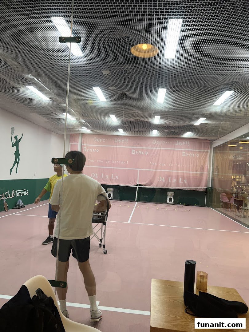 Two individuals on a vibrant pink indoor tennis court, possibly training or playing.