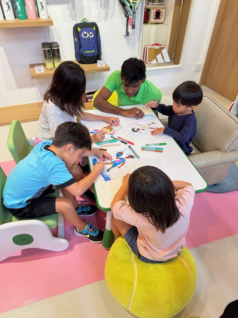 Children and an adult coloring at a table in a tennis-themed shop interior.