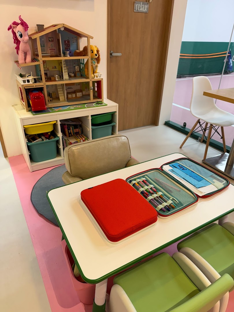 A vibrant children's play area with a dollhouse and activity table, adjacent to a tennis court.