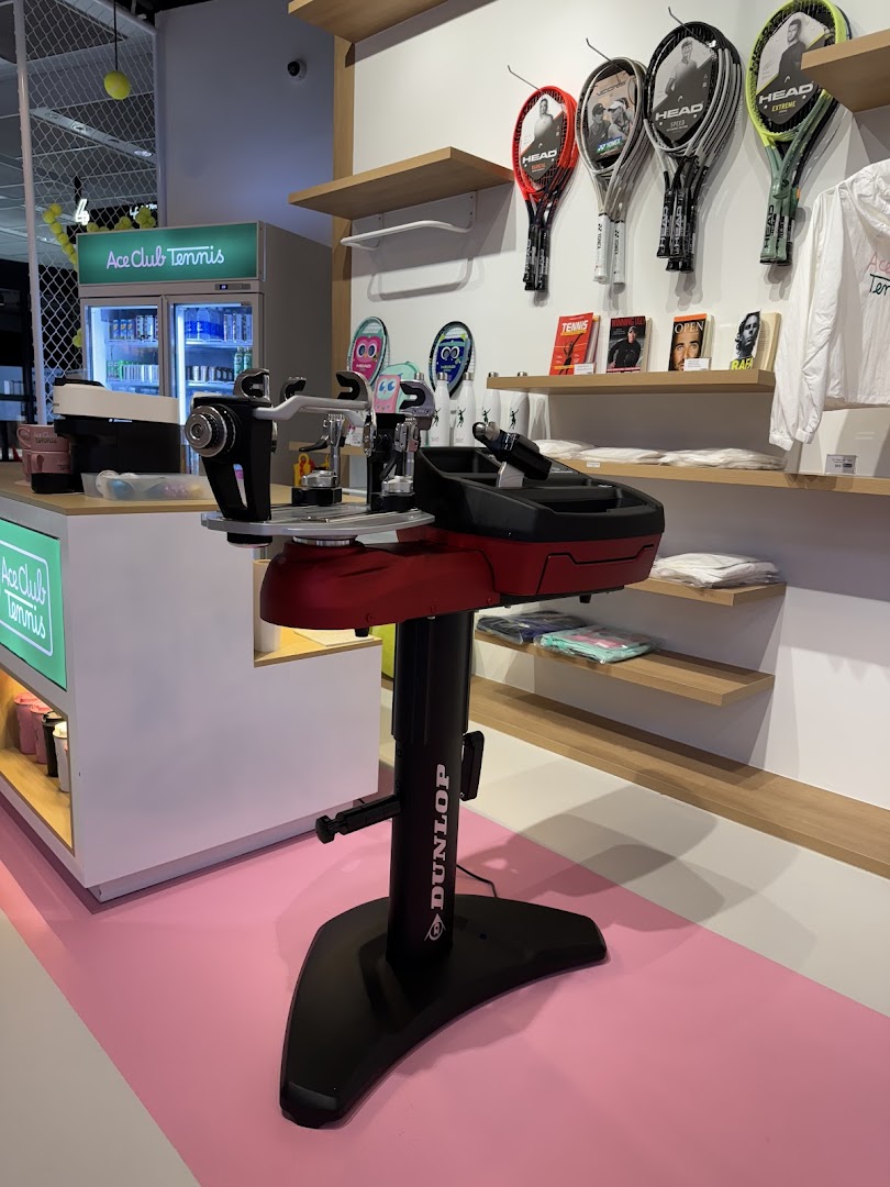 An interior view of Ace Club Tennis, featuring a stringing machine and tennis equipment displays.