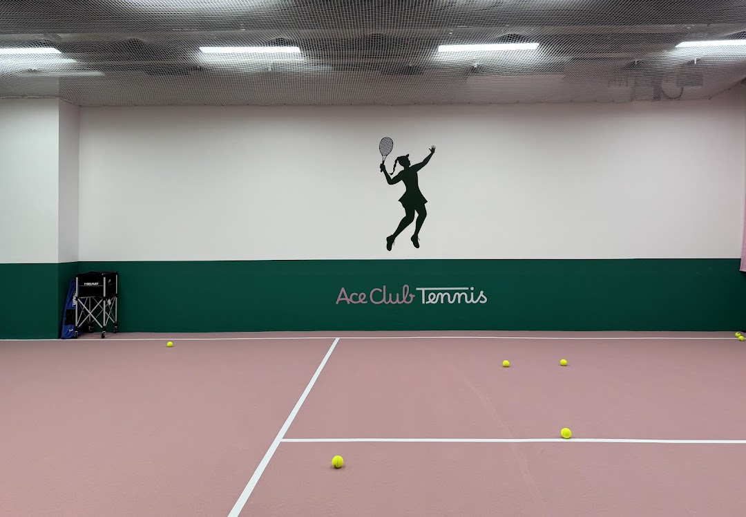 An indoor tennis court with the Ace Club Tennis logo and a tennis player silhouette on the wall.