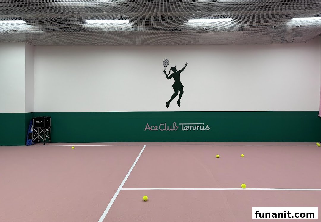 An indoor tennis court with the Ace Club Tennis logo and a tennis player silhouette on the wall.