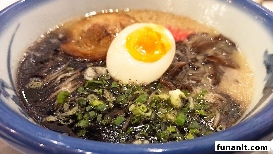 A close-up of a delicious bowl of ramen with a soft-boiled egg, pork, and green onions.