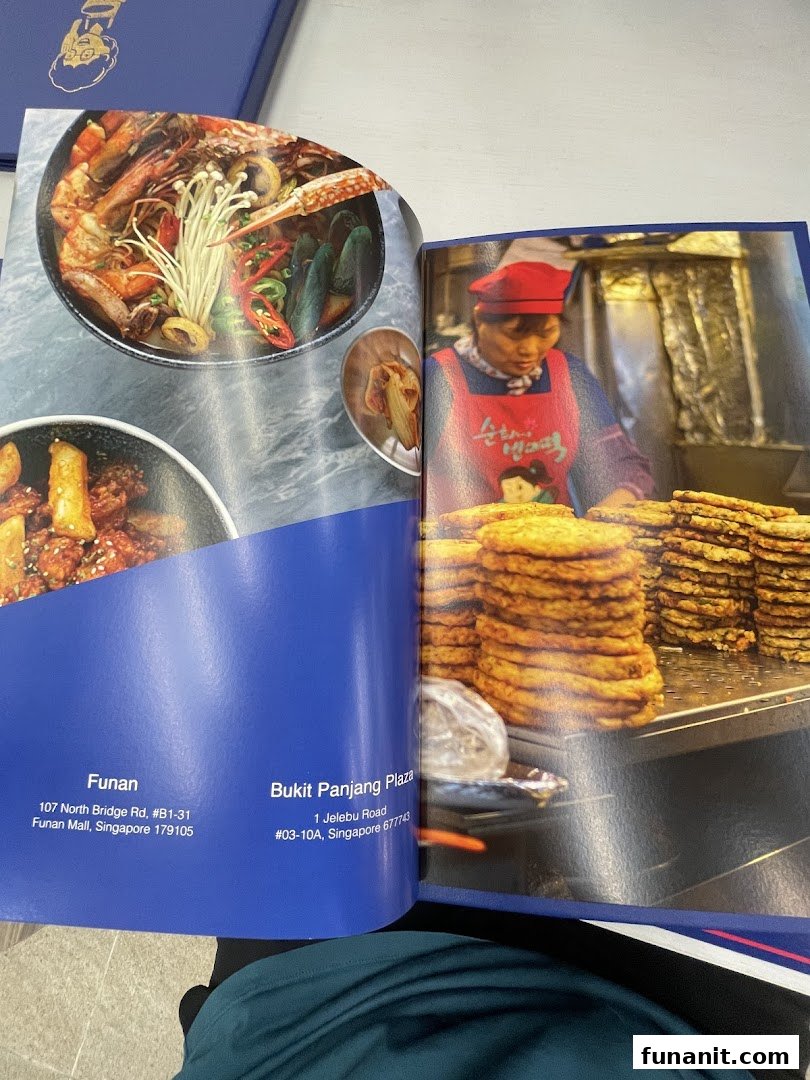 An open brochure showcasing vibrant Korean dishes like seafood stew and tteokbokki, with shop location details.