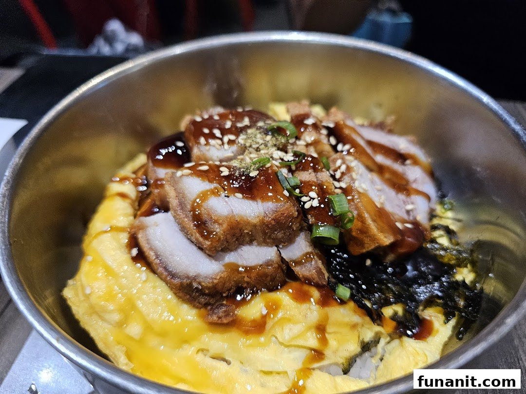 A close-up of a delicious rice bowl with crispy pork, scrambled egg, and seaweed.