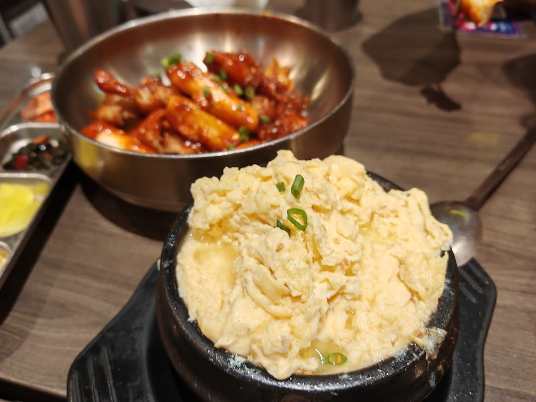 Close-up of delicious Korean steamed egg and spicy rice cakes with banchan on a wooden table.