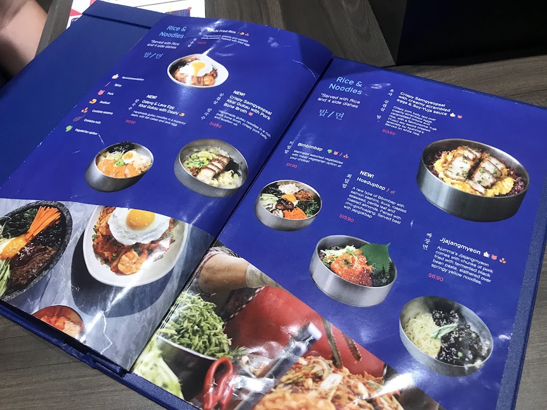 A vibrant menu from Ajummas, showcasing various Korean rice and noodle dishes with enticing photos.
