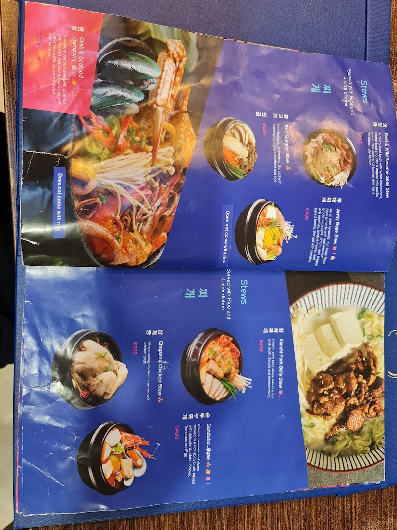 A detailed view of a Korean restaurant menu from Ajummas, showcasing various stew dishes.