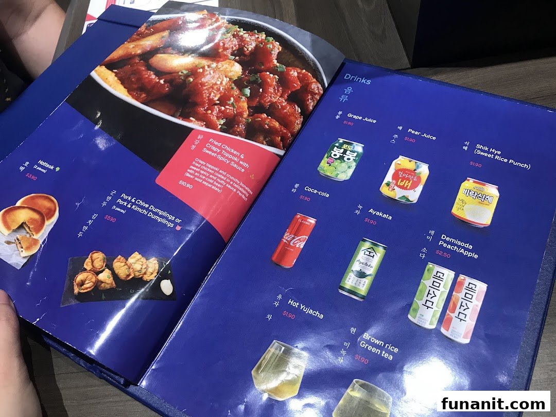 A close-up view of a vibrant blue menu from Ajummas, showcasing Korean food and drink options.