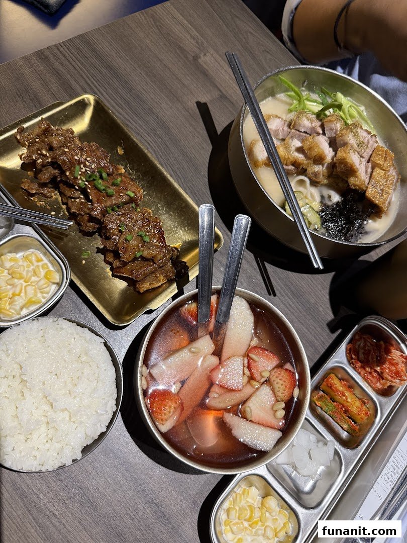 A table laden with delicious Korean dishes including BBQ, noodle soup, rice, and banchan.