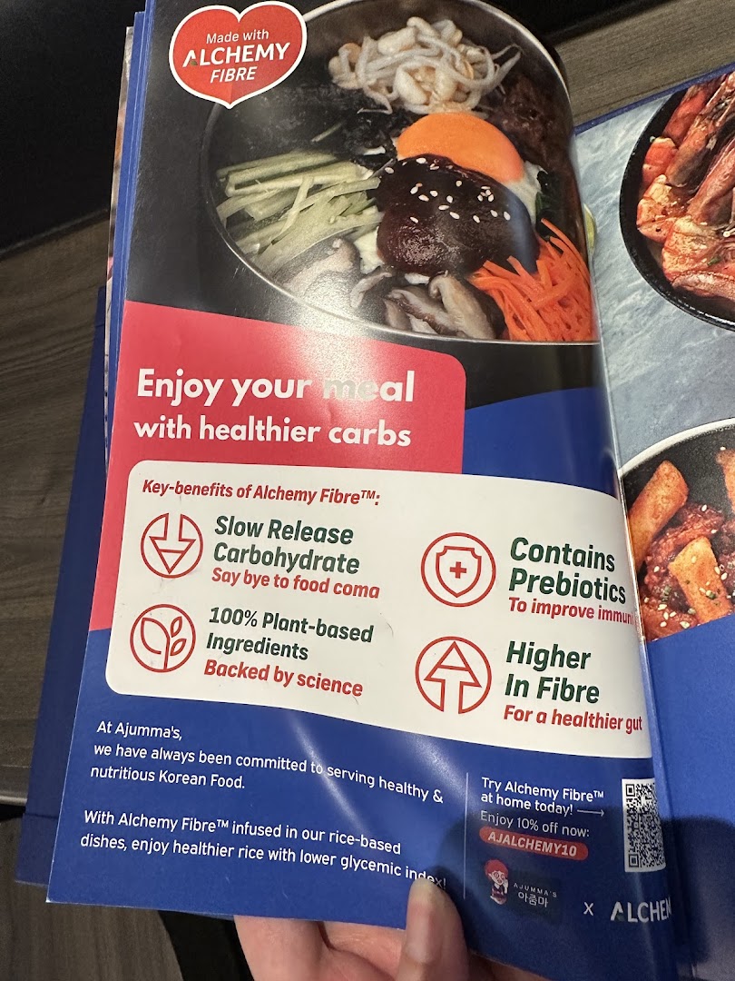 A promotional page for Ajumma's, highlighting a Korean dish and the health benefits of Alchemy Fibre.