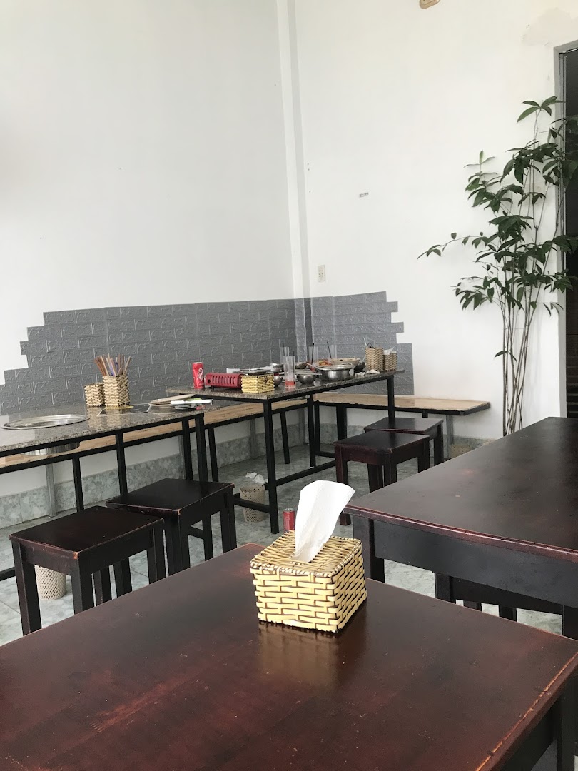 Interior view of Ajummas restaurant with dark wooden tables, stools, and cooking stations.