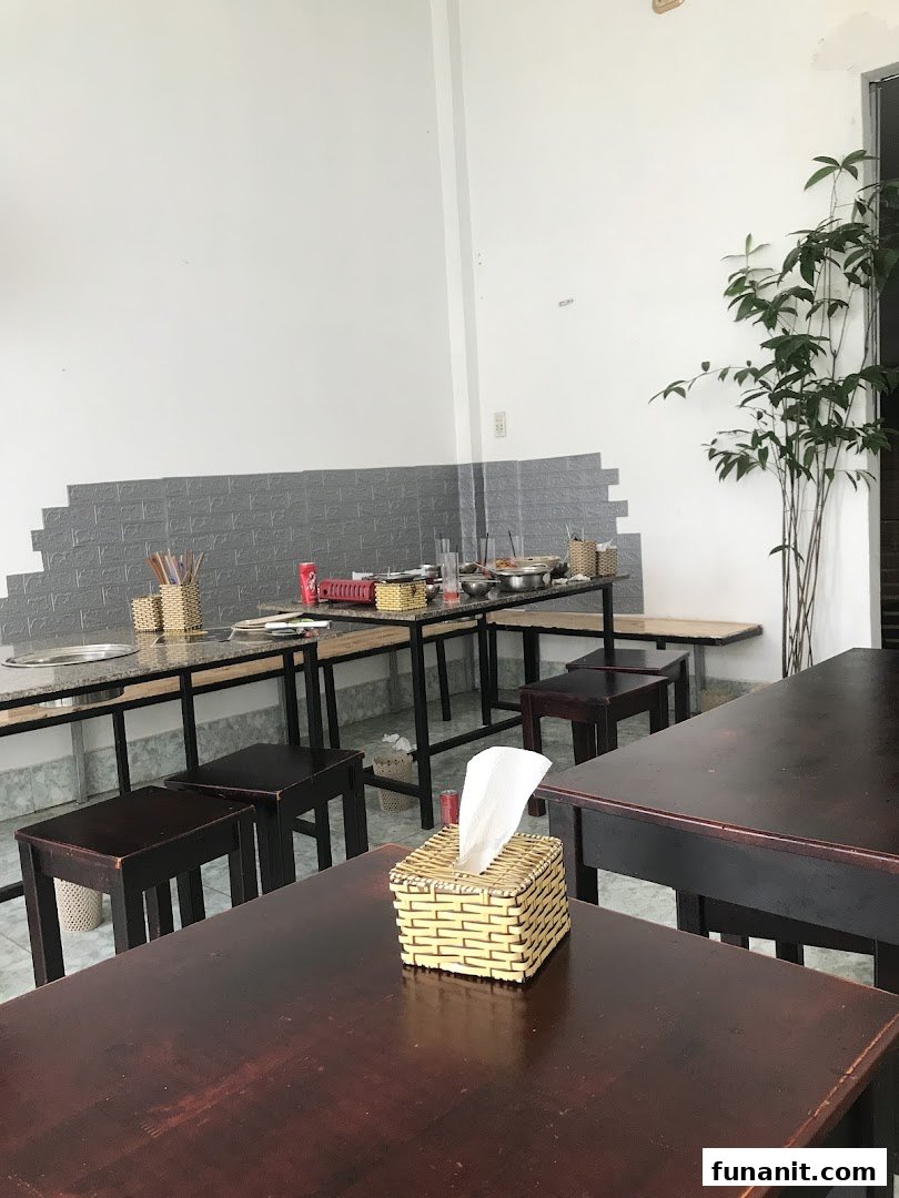 Interior view of Ajummas restaurant with dark wooden tables, stools, and cooking stations.