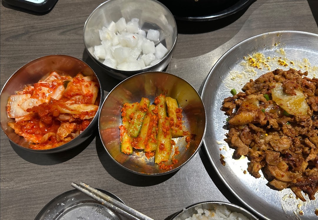 A close-up of delicious Korean banchan and a main dish of spicy stir-fried meat on a table.