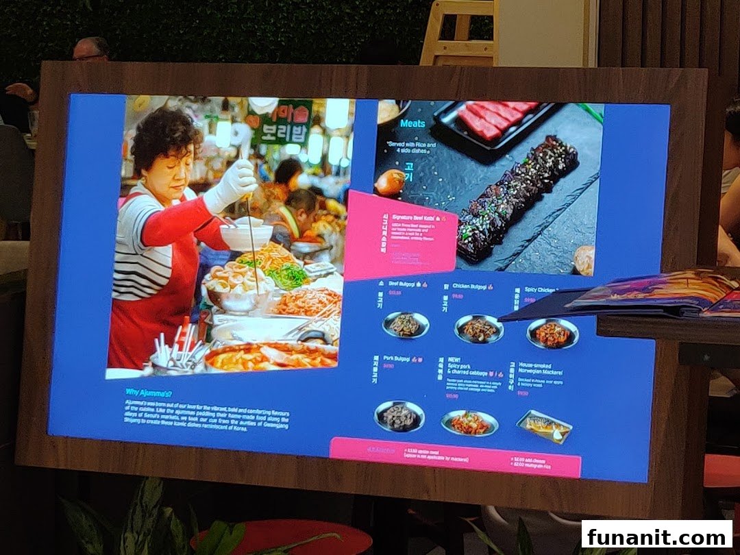 A digital menu board for Ajummas, showcasing Korean dishes with vibrant imagery and descriptions.