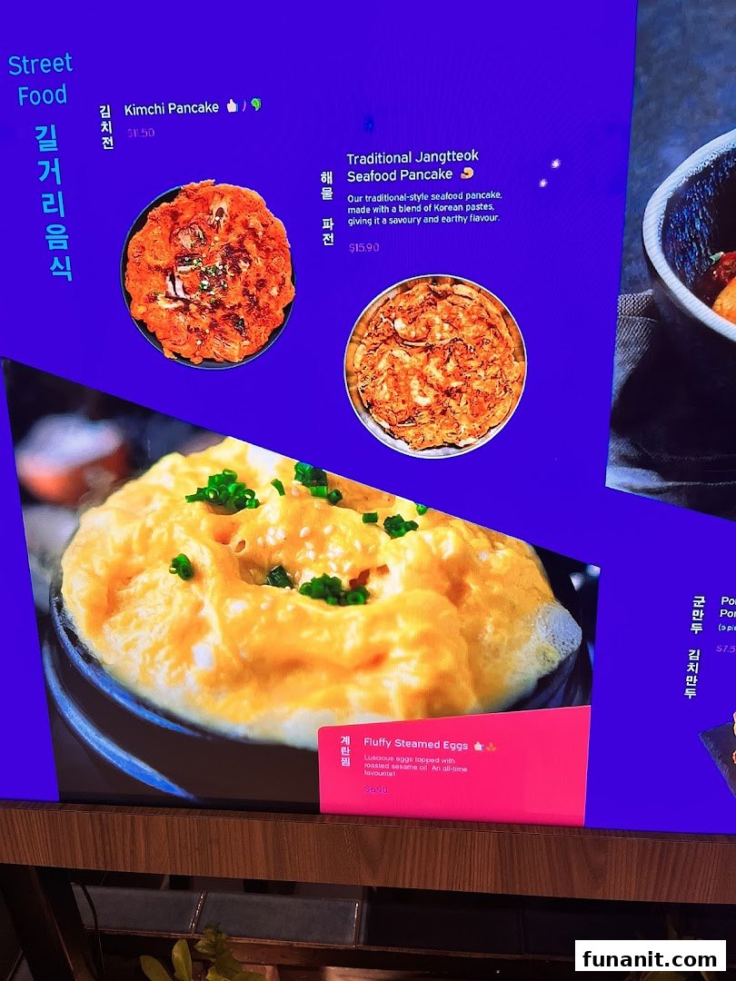 Digital menu board displaying Korean street food items like pancakes and steamed eggs with prices.