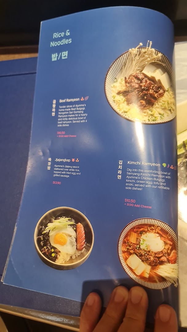 A close-up of a menu page from Ajummas featuring Korean rice and noodle dishes.