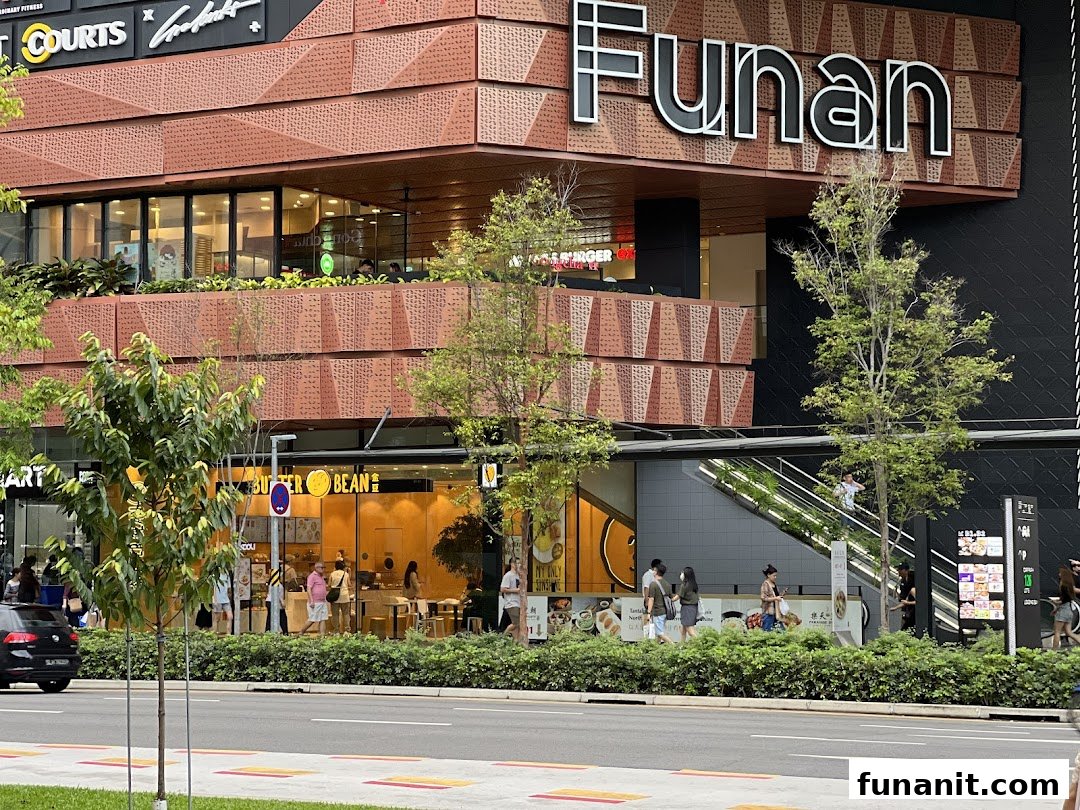 Exterior view of Funan mall showing its modern facade, ground-level shops like Butter Bean, and pedestrians.