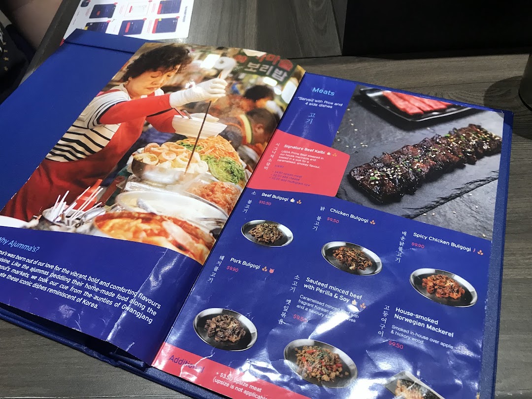 A blue menu displaying Korean meat dishes with prices and descriptions from Ajummas.
