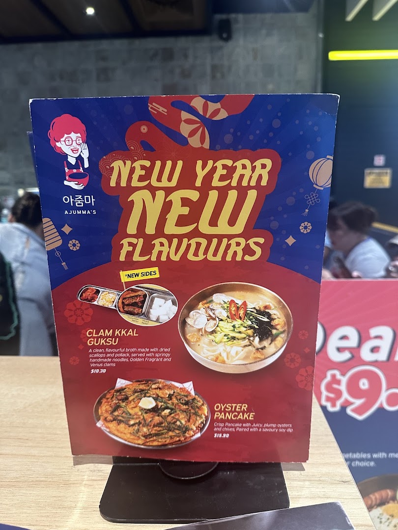 A table-top menu stand from Ajummas featuring 'New Year New Flavours' specials.