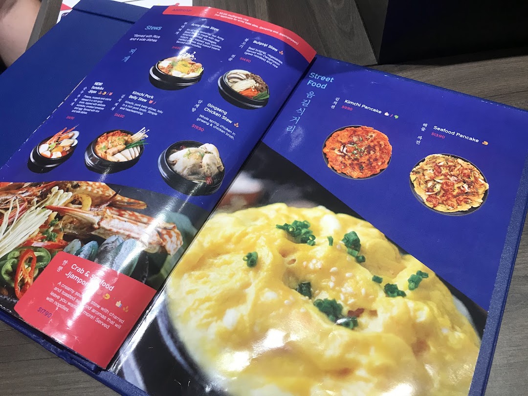 An open menu displaying various Korean stews and street food items with prices.