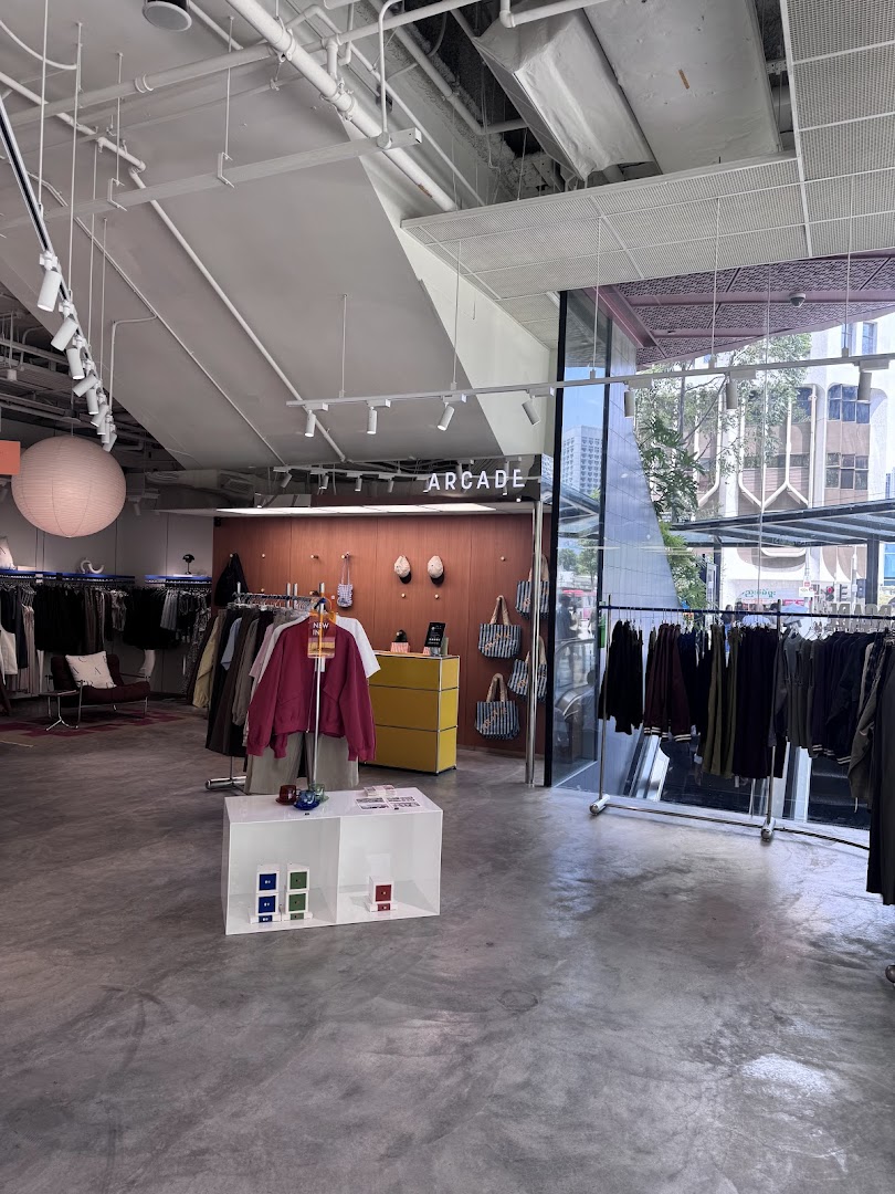 Interior view of Alchemist Funan, a modern clothing store with racks of apparel and minimalist decor.
