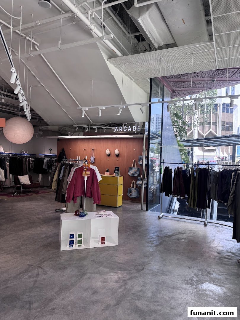 Interior view of Alchemist Funan, a modern clothing store with racks of apparel and minimalist decor.