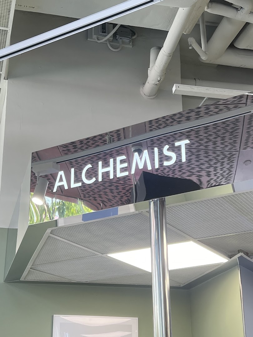 Close-up of the illuminated 'ALCHEMIST' sign within the shop interior.