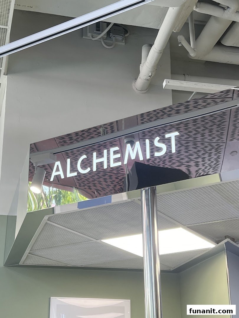 Close-up of the illuminated 'ALCHEMIST' sign within the shop interior.